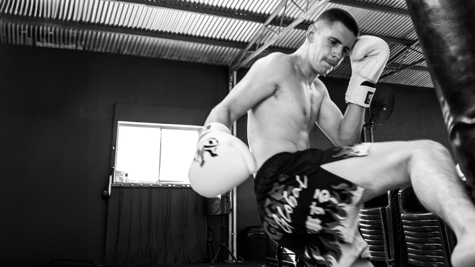 Young man kicking heavy bag