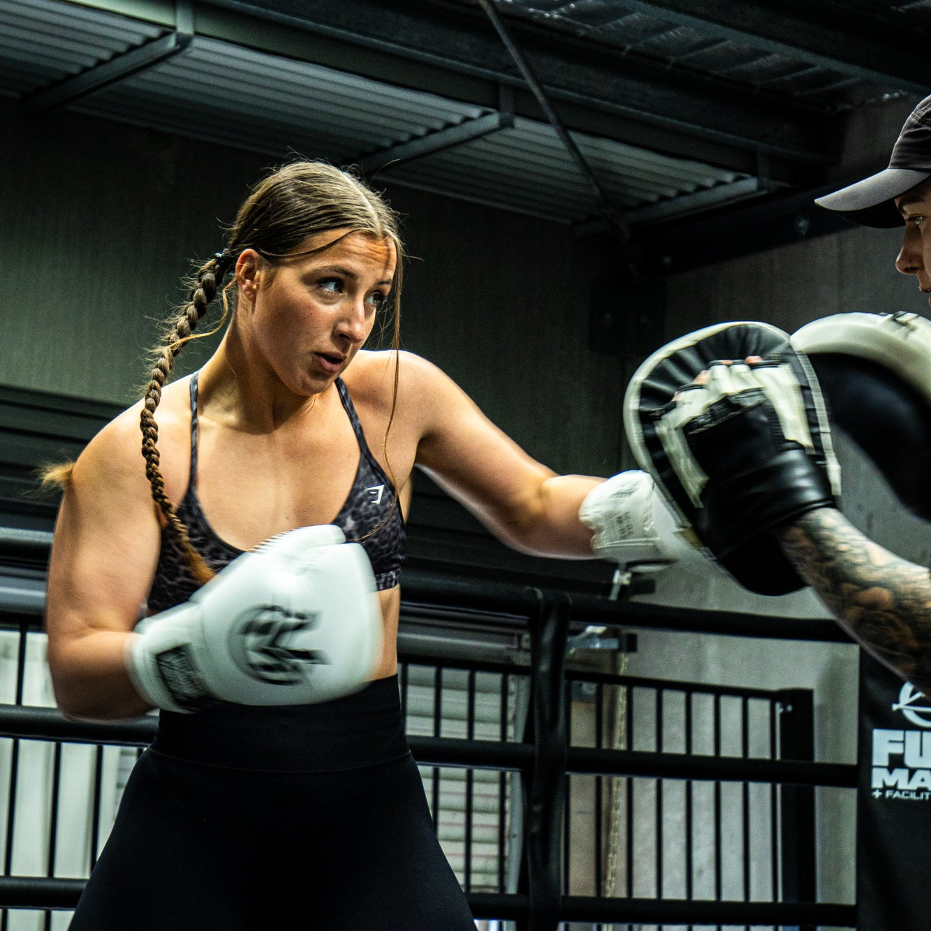 Two boxers in a training session inside a boxing ring.