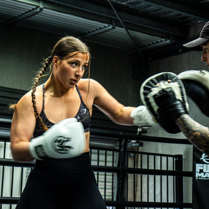 Two boxers in a training session inside a boxing ring.
