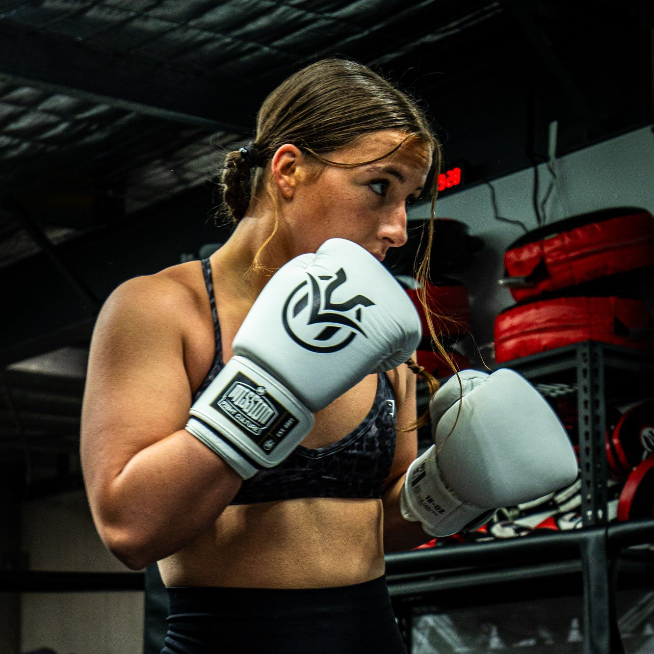 female boxer wearing white boxing gloves ready for sparring in a gym.